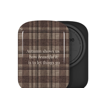 Custom ChargePod/batterie, featuring a brown and beige plaid patterned lid with the text 'Autumn shows us how beautiful it is to let things go' in white script. The compact is shown open, revealing a black circular powder pan behind it on a plain white background.