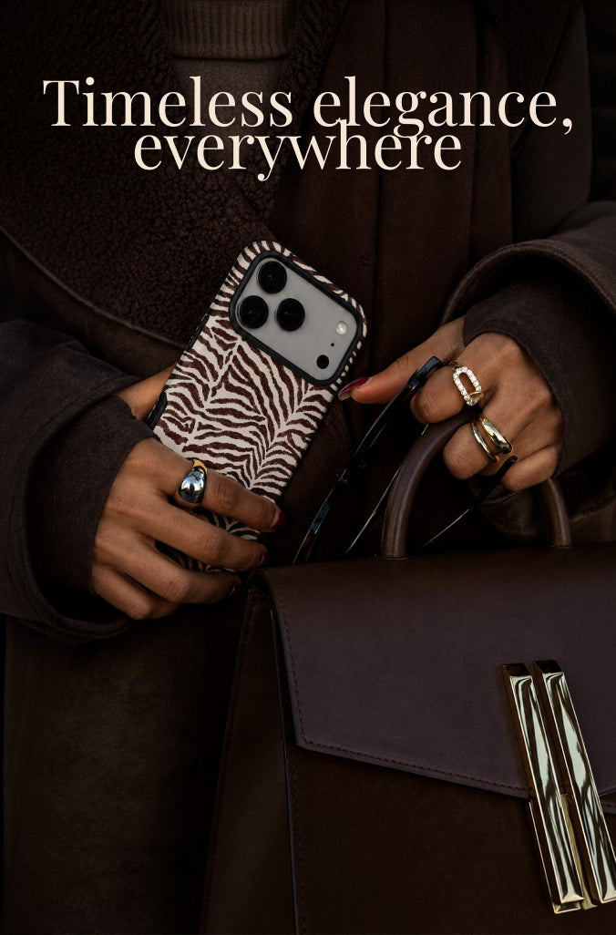 A person in a dark brown coat holds a zebra-print phone case and a dark brown structured handbag with gold-tone hardware. The text 'Timeless elegance, everywhere' appears at the top.